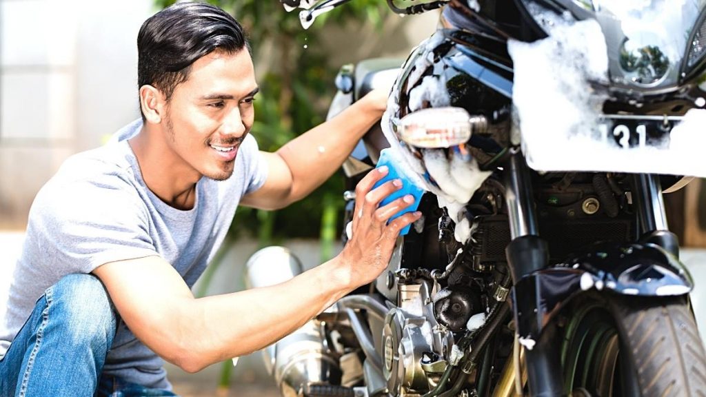 Gambar seorang pria sedang mencuci kendaraan motor